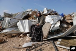 A Bedouin woman sit on demolished structure of a house in the Bedouin village of Umm al-Hiran, near the southern city of Beersheba, Israel Wednesday, Jan. 18, 2017.