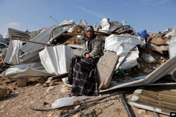 A Bedouin woman sit on demolished structure of a house in the Bedouin village of Umm al-Hiran, near the southern city of Beersheba, Israel Wednesday, Jan. 18, 2017.