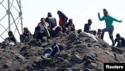 FILE - Migrants gather on a heap of loose earth near the former "jungle" in Calais, France, June 1, 2017.