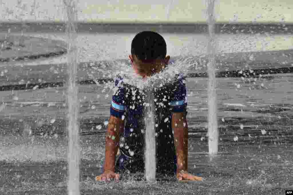 Seorang anak mendinginkan diri di sebuah pancuran di Milan, saat gelombang hawa panas melanda Eropa dengan temperatur mencapai hampir 40 derajat Celcius.