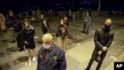 A small numbers of Georgian Orthodox Church worshippers, wearing face masks to protect against coronavirus, observe social distancing guidelines, attend a Mass celebrating Orthodox Easter outside the Trinity cathedral in Tbilisi, Georgia, April 
