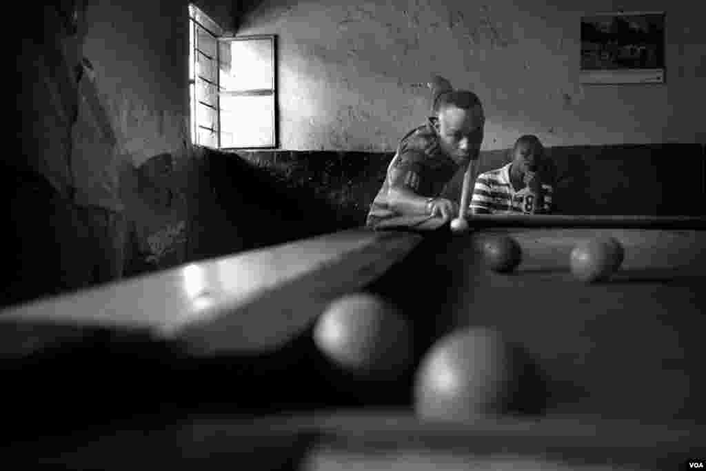 Kuitonda David, age 24, plays pool in the billiards hall where he works, Gibiloso, Kigali, Rwanda, Nov. 27, 2013. (Hamada Elrasam for VOA)