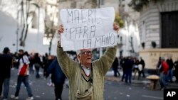 A man holds a sign that reads in Spanish "Macri stop it" during a protest in Plaza de Mayo, Buenos Aires, Argentina, Aug. 22, 2017. 