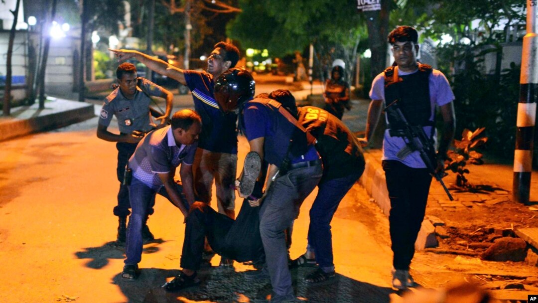 People help an unidentified injured person after a group of gunmen attacked a restaurant popular with foreigners in the Bangladeshi capital Dhaka.