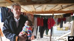 FILE - U.N. special adviser Jan Egeland holds a Syrian baby during his visit to a refugee camp in the town of Marej in the Bekaa valley, east Lebanon, Feb. 25, 2015. 