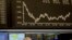 FILE - A broker watches her screens under the curve of the German stock index DAX in Frankfurt, Germany.