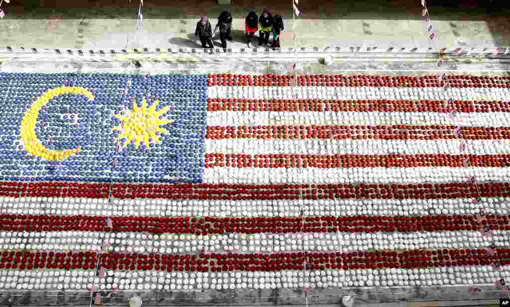 Students watch a giant Malaysian national flag made of coconut shells at Selayang in Kuala Lumpur, Malaysia, Aug. 28, 2017. 