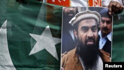FILE - A supporter of Shiv Sena, a Hindu hardline group, holds Pakistan's national flag and a portrait of Zaki-ur-Rehman Lakhvi during a protest against Lakhvi's release, in New Delhi, April 11, 2015.