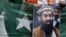 FILE - A supporter of Shiv Sena, a Hindu hardline group, holds Pakistan's national flag and a portrait of Zaki-ur-Rehman Lakhvi during a protest against Lakhvi's release, in New Delhi, April 11, 2015.
