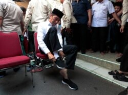Indonesian President Joko Widodo put his sneakers back on after attending a Friday prayer at a mosque in Jakarta, Indonesia, July 26, 2019.
