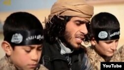 А YouTube screen grab from an undated Islamic State propaganda video shows an IS recruiter with two child soldiers. Children as young as four years old are reportedly being trained to serve in roles ranging from spies, to front line soldiers, to suicide bombers.