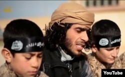 FILE - А screen grab from an Islamic State propaganda video shows an Islamic State recruiter with two child soldiers at an unknown location. Experts warn that not enough thought is being given about what to do with so-called “cubs of the caliphate” — both the offspring of foreign recruits as well as Syrian and Iraqi children enlisted into terror ranks.