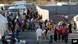 Newly-arrived Syrian refugees walk to their tents in the Turkish border town of Reyhanli in Hatay province, as others who are already placed rest in front of their tents (File)