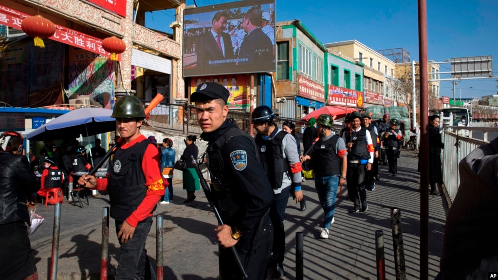 一名中国警察带领一队武装民兵在新疆和田的市场外巡逻。（2017年11月3日） 