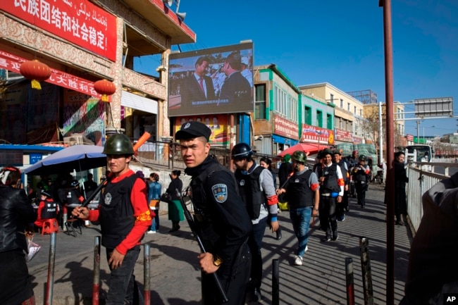 一名中国警察带领一队武装民兵在新疆和田的市场外巡逻。（2017年11月3日）