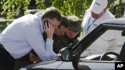 Alexander Hug, deputy head of the OSCE mission to Ukraine, left, his colleagues and a pro-Russian rebel, 2nd right, examine a map as they try to estimate security conditions around the site of the crashed Malaysia Airlines Flight 17 in the city of Donetsk