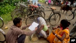 People whose names were left out in the National Register of Citizens (NRC) draft fill their forms to file appeals near a NRC center on the outskirts of Gauhati, India, Monday, Aug. 13, 2018. (AP Photo/Anupam Nath)