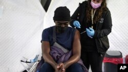 A migrant receives a booster Johnson and Johnson vaccine against COVID-19 at Karatepe refugee camp, on the northeastern Aegean island of Lesbos, Greece, Dec. 15, 2021.