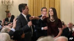 Una becaria de la Casa Blanca trata de retirarle el micrófono al corresponsal de CNN, Jim Acosta, mientras este intenta hacerle una pregunta al presidente Donald Trump durante una conferencia de prensa en la Casa Blanca en Washington, el 7 de noviembre de 2018.