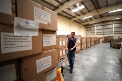 FILE - A worker pulls a cart of coronavirus aid items being prepared for shipment, at a World Health Organization facility, part of the International Humanitarian City, in Dubai, United Arab Emirates, March 5, 2020.