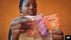 FILE —A Ugandan businesswoman who sells cereals counts Ugandan Shilling banknotes in Kampala, Uganda, February 27, 2014. 