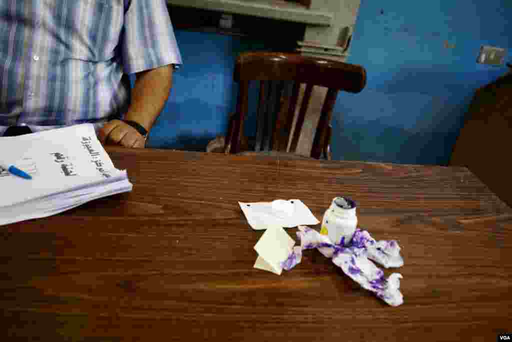 An ink bottle and tissues on a table beside a poll worker. Egyptians dip their index finger into ink after voting as a way to avoid voter fraud, Cairo, Egypt, June 16, 2012. (Y. Weeks/VOA)