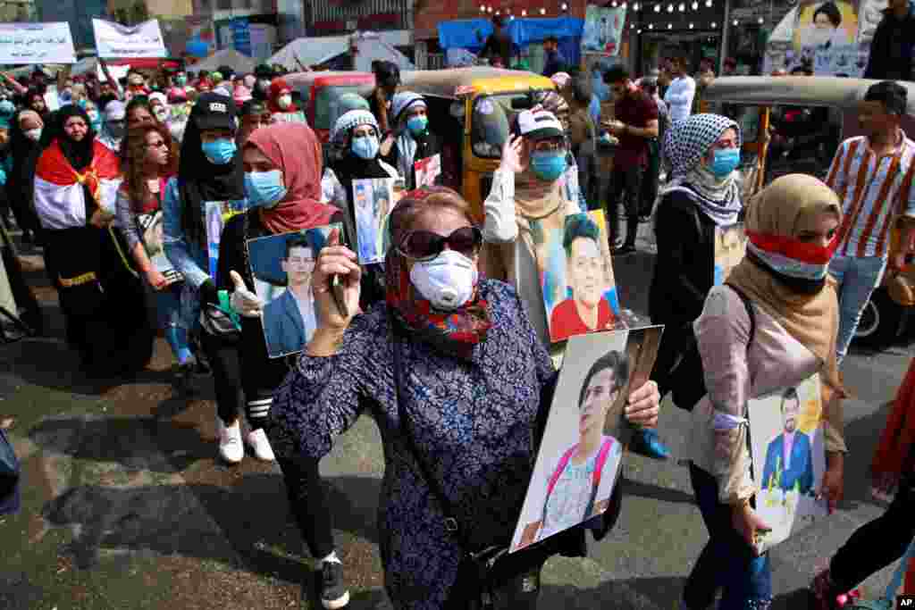 Manifestantes antigubernamentales, incluidos algunos con una máscara protectora debido al nuevo coronavirus, muestran imágenes de personas que han sido asesinadas en manifestaciones antigubernamentales y cantan por los derechos de las mujeres en el Día Internacional de la Mujer en la Plaza Tahrir, Bagdad, Irak, el domingo, 8 de marzo de 2020. 