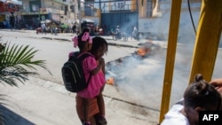 La gente huye de la violencia de pandillas en un barrio de Puerto Príncipe mientras se manifiesta contra el gobierno el 20 de febrero de 2025.