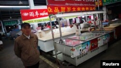 Seorang pria berjalan melintasi sebuah kios penjualan daging yang tutup di distrik Minhang district, selatan Shanghai (Foto: dok). Kios ini milik pria 27 tahun yang meninggal akibat virus flu burung H7N9 bulan lalu.China melaporkan adanya kasus baru tersebarnya virus ini di propinsi Henan, Minggu (14/4).