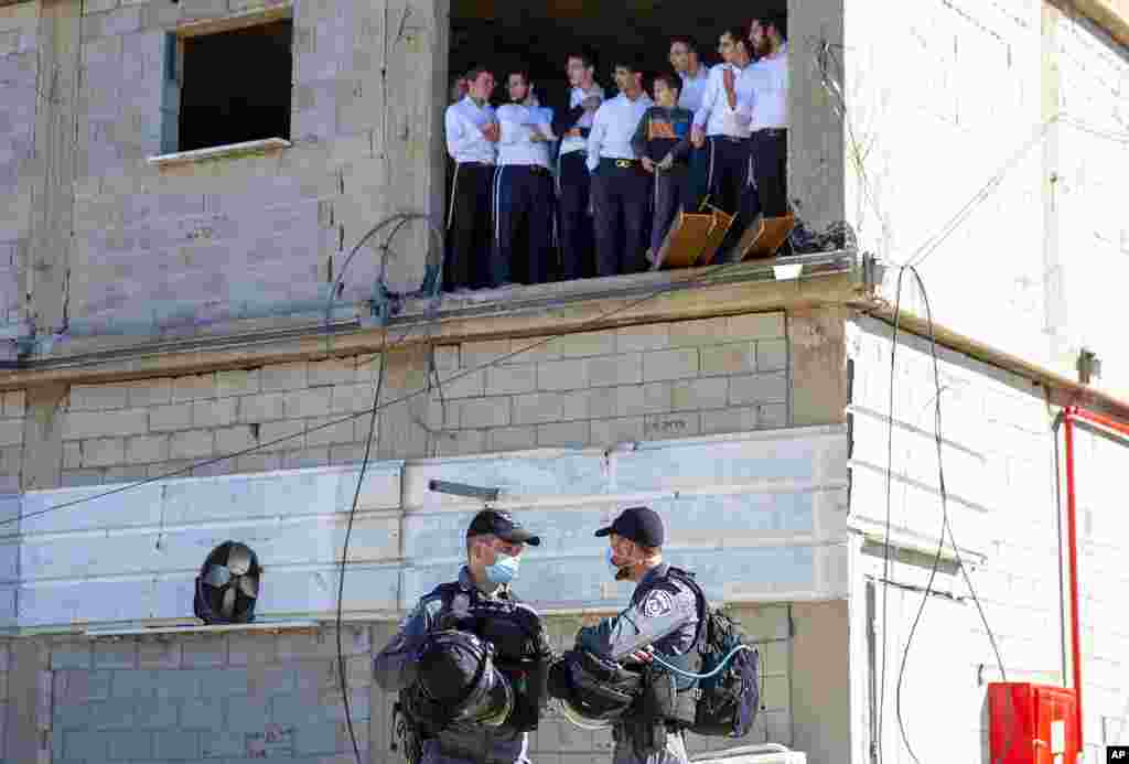 Ultra-Orthodox Jewish seminary students look at Israeli police as they arrive to shutter the Jewish seminary that had opened in violation of coronavirus lockdown rules in Ashdod, Israel. 