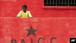 Boy stands by sign of Guinea-Bissau's ruling political party on election day in the capital, Bissau, March 18, 2012.