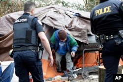 Leroy Henry, center, steps out of his tent in the woods to talk with police officer Kevin Davis, left, and Sgt. Mike Braley in Everett, Washington, Feb. 16, 2017.