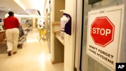 FILE- A sign urging staff and patients to wash their hands hangs on the wall as a patient is wheeled through the emergency room at Greater Baltimore Medical Center in Towson, Maryland, Nov. 3, 2009.