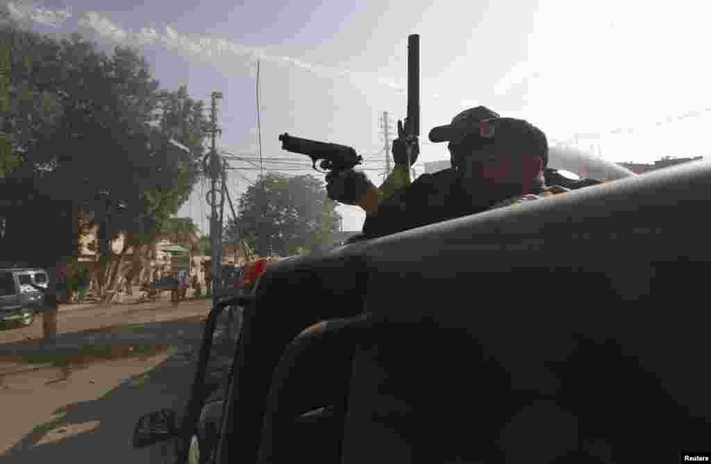 A policeman uses his gun to disperse protesters during a protest against satirical French weekly Charlie Hebdo, which featured a cartoon of the Prophet Muhammad on the cover after the terror attack in Paris, Karachi, Pakistan, Jan. 16, 2015.