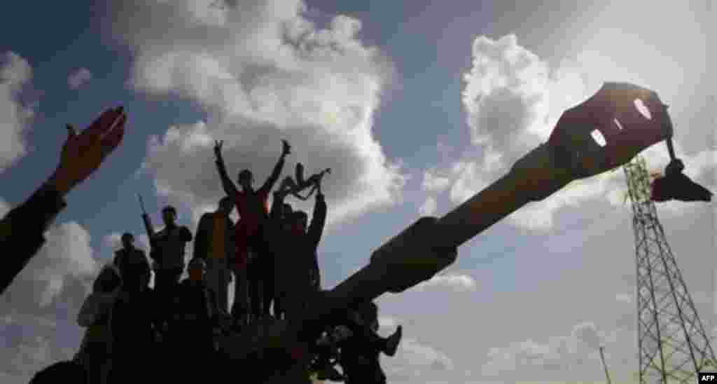 Libyan people celebrate on a tank belonging to the forces of Moammar Gadhafi in the outskirts of Benghazi, eastern Libya, Sunday, March 20, 2011. The U.S. military said 112 Tomahawk cruise missiles were fired from American and British ships and submarine