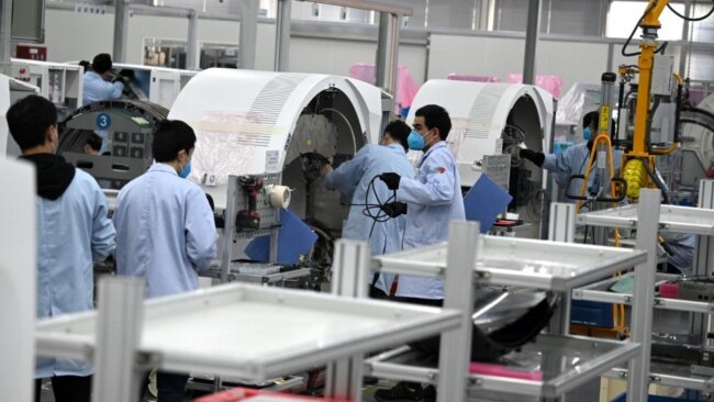 上海生产医疗设备的西门子工厂工人戴着口罩在生产线上工作。（2020年2月24日）