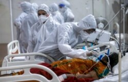 Petugas kesehatan mencoba menyesuaikan masker oksigen seorang pasien di rumah sakit lapangan jumbo BKC, salah satu fasilitas COVID-19 terbesar di Mumbai, India, 6 Mei 2021. (Foto: AP)