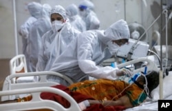 Petugas kesehatan mencoba menyesuaikan masker oksigen seorang pasien di rumah sakit lapangan jumbo BKC, salah satu fasilitas COVID-19 terbesar di Mumbai, India, 6 Mei 2021. (Foto: AP)