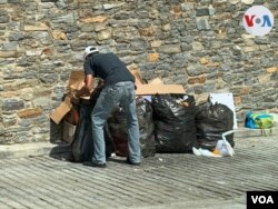 Un hombre busca comida en bolsas de basura ubicadas en las inmediaciones de edificios en una zona acomodada del este de Caracas. Agosto, 2021. Foto: Carolina Alcalde - VOA.