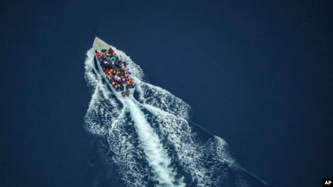 Migrants navigate on an overcrowded wooden boat in the Central Mediterranean Sea between North Africa and the Italian island of Lampedusa, Oct. 2, 2021, as seen from aboard the humanitarian aircraft Seabird.