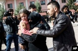 A Turkish man helps a Syrian woman carrying a wounded Syrian girl to a hospital in Kilis, Turkey, Feb. 15, 2016.