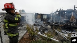 Seorang petugas pemadam kebakaran mengamati rumah-rumah yang hancur akibat gempa di Napa, California, AS (24/8). 