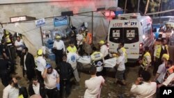 Israeli security officials and rescuers carry the body of a victim who died in a stampede during Lag B'Omer celebrations at Mount Meron in northern Israel, April 30, 2021.