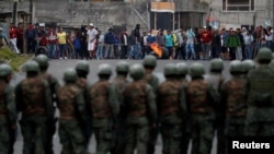 Soldiers line up as people block a road during protests after Ecuador's President Lenin Moreno's government ended four-decade-old fuel subsidies.