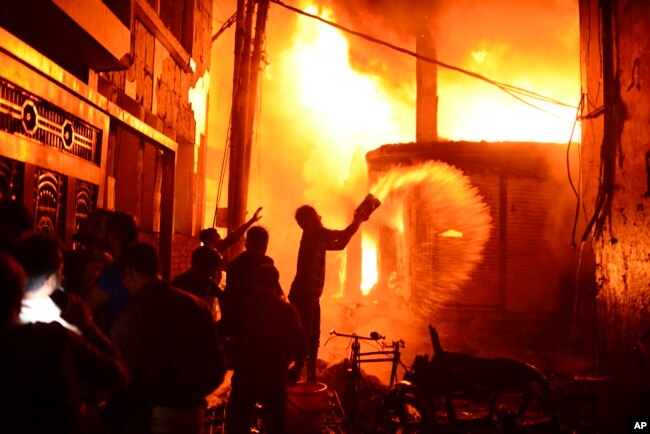 Para petugas pemadam kebakaran dan warga berusaha memadamkan api di sebuah pabrik garmen yang terbakar di Dhaka, Bangladesh, 20 Februari 2019.