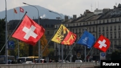 FILE - Swiss and Canton of Geneva flags are seen flying on the Mont-Blanc bridge in Geneva, Switzerland, Oct. 11, 2016. Swiss lawmakers plan to submit to government a new broad EU treaty that would replace patchwork of bilateral deals now under strain from immigration.