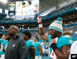 Miami Dolphins defensive end Robert Quinn raises his right fist during the singing of the National Anthem, before the start of an NFL preseason football game against the Tampa Bay Buccaneers, Aug. 9, 2018 in Miami Gardens, Fla.