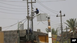 FILE - Ministry of Electricity workers try to maintain the power transmission network in Basra, Iraq, July 30, 2020. 