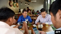 រូបឯកសារ៖ បុរសមួយក្រុមកំពុងប្រើប្រព័ន្ធអ៊ីនធឺណិតតាមទូរស័ព្ទទំនើបរបស់ពួកគេ នៅក្នុងហាងកាហ្វេមួយ នៅរាជធានីភ្នំពេញ កាលពីថ្ងៃទី១៧ ខែតុលា ឆ្នាំ២០១៨។