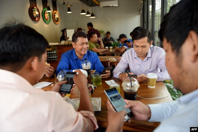 រូបឯកសារ៖ បុរសមួយក្រុមកំពុងប្រើប្រព័ន្ធអ៊ីនធឺណិតតាមទូរស័ព្ទទំនើបរបស់ពួកគេ នៅក្នុងហាងកាហ្វេមួយ នៅរាជធានីភ្នំពេញ កាលពីថ្ងៃទី១៧ ខែតុលា ឆ្នាំ២០១៨។
